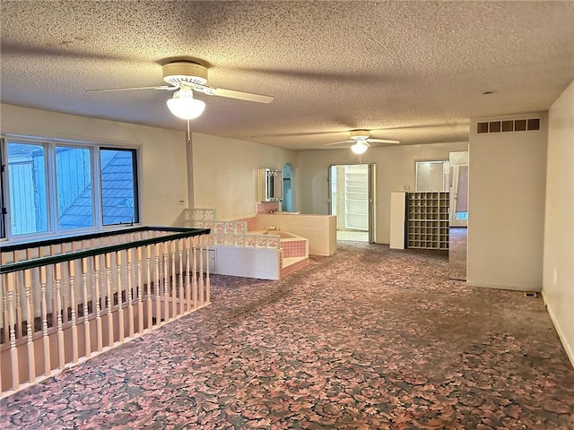 carpeted spare room with ceiling fan and a textured ceiling