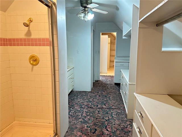 bathroom with ceiling fan, a tile shower, and vaulted ceiling