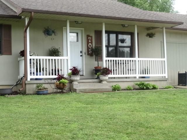 entrance to property featuring covered porch and a yard