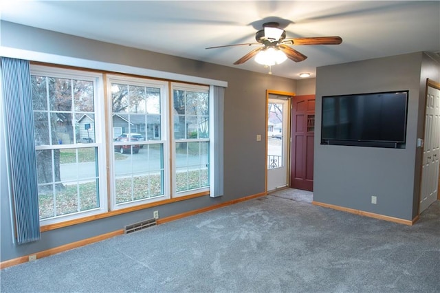 unfurnished living room with plenty of natural light, ceiling fan, and carpet floors