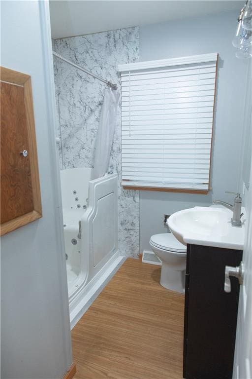 bathroom featuring hardwood / wood-style floors, vanity, toilet, and a tile shower