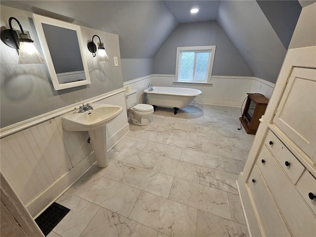 bathroom with a washtub, vaulted ceiling, and toilet