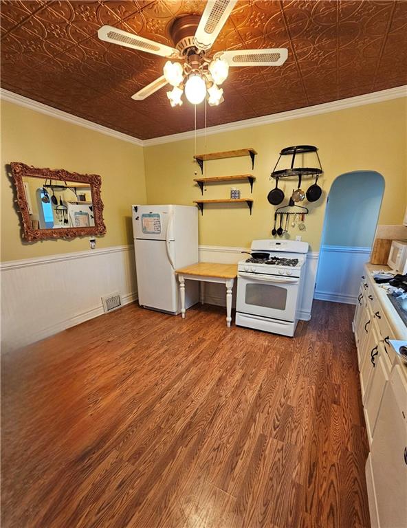 kitchen with white cabinets, white appliances, hardwood / wood-style flooring, and crown molding