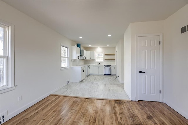 kitchen featuring white cabinetry, dishwasher, wall chimney exhaust hood, backsplash, and light hardwood / wood-style floors