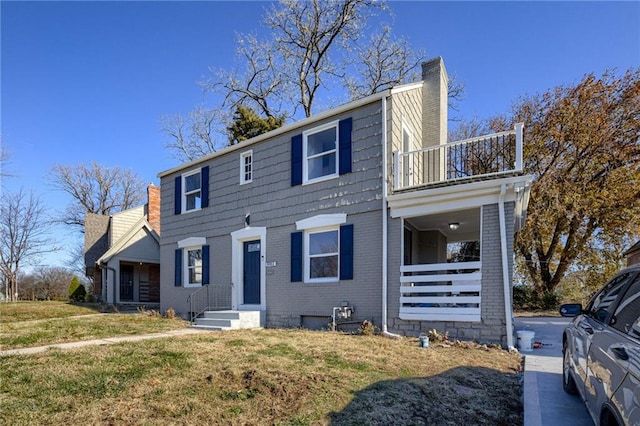 view of front of home with a balcony and a front yard