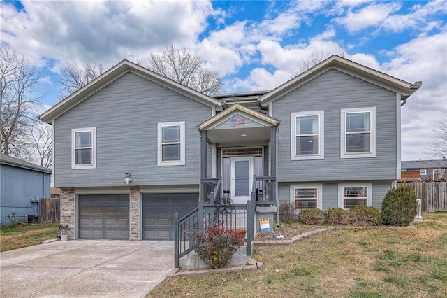 raised ranch featuring a garage, central air condition unit, and a front lawn