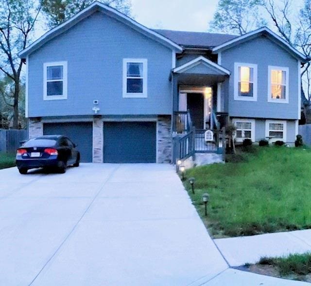 raised ranch with a front lawn and a garage