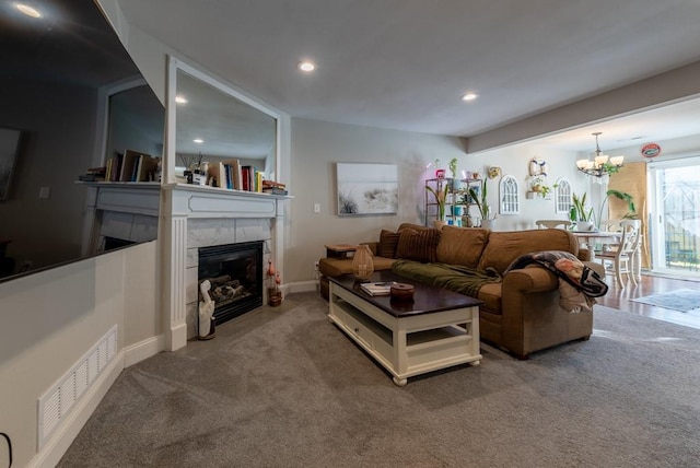 carpeted living room featuring a fireplace and a notable chandelier