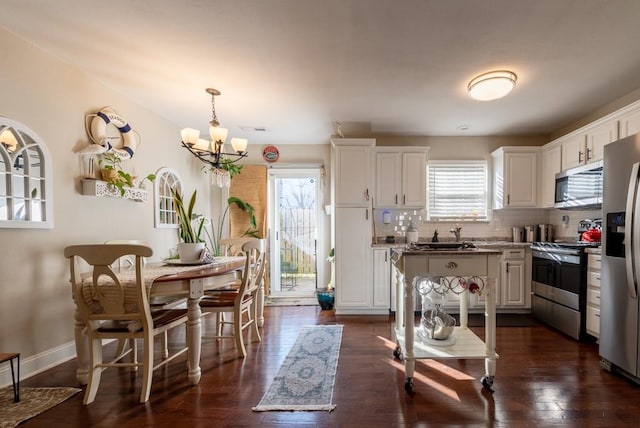 kitchen featuring dark wood-type flooring, an inviting chandelier, decorative backsplash, appliances with stainless steel finishes, and white cabinetry