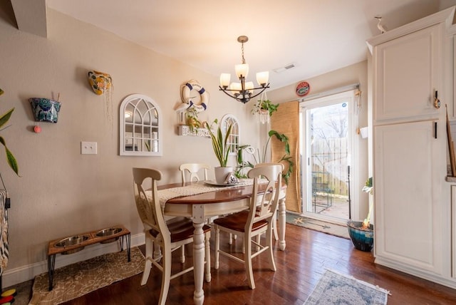 dining space featuring dark hardwood / wood-style floors and an inviting chandelier