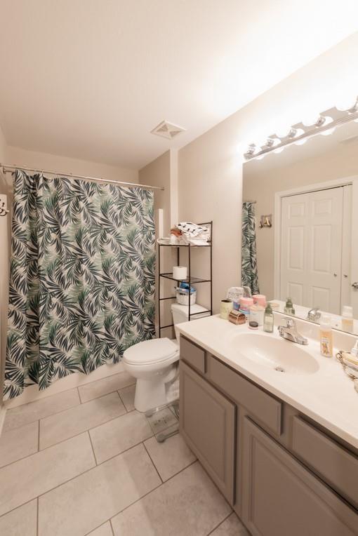 bathroom with toilet, vanity, and tile patterned floors