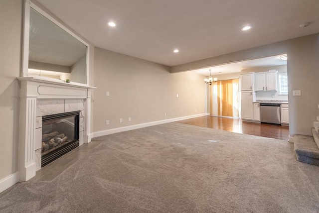 unfurnished living room featuring carpet flooring, a premium fireplace, and a notable chandelier