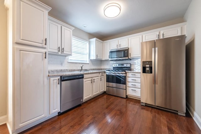 kitchen with decorative backsplash, white cabinetry, dark wood-type flooring, and appliances with stainless steel finishes