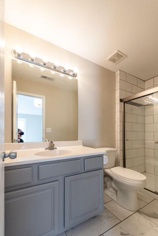 bathroom featuring vanity, toilet, and an enclosed shower