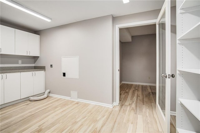 laundry area with hookup for an electric dryer, light hardwood / wood-style floors, and cabinets