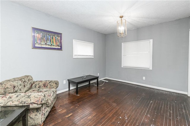 living area featuring a textured ceiling, dark hardwood / wood-style flooring, and an inviting chandelier