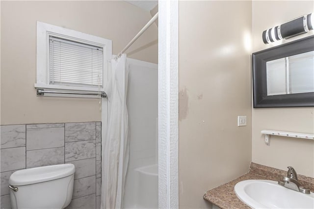 bathroom with curtained shower, vanity, tile walls, and toilet