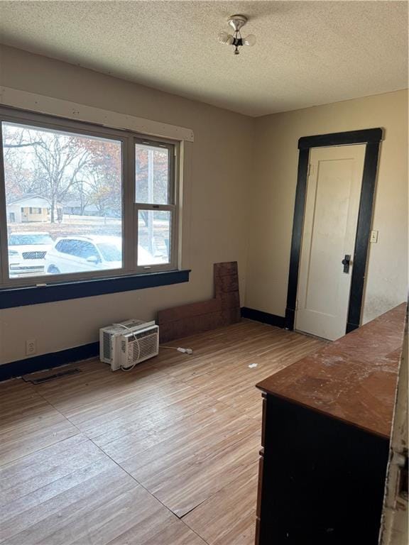 empty room featuring plenty of natural light, a textured ceiling, and light wood-type flooring