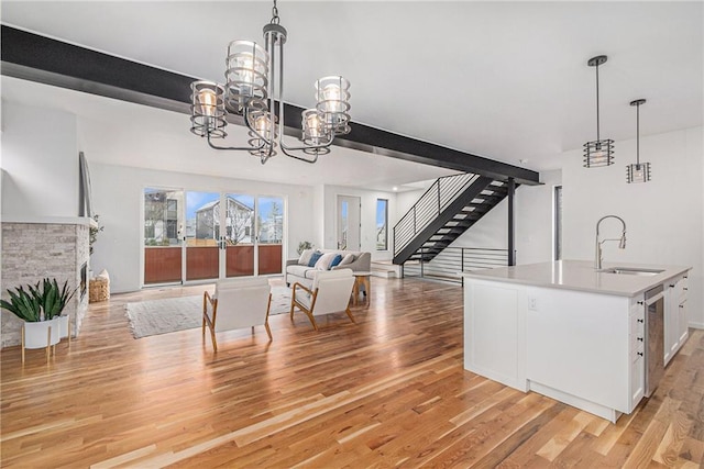 dining area featuring sink, beam ceiling, a fireplace, and light hardwood / wood-style floors