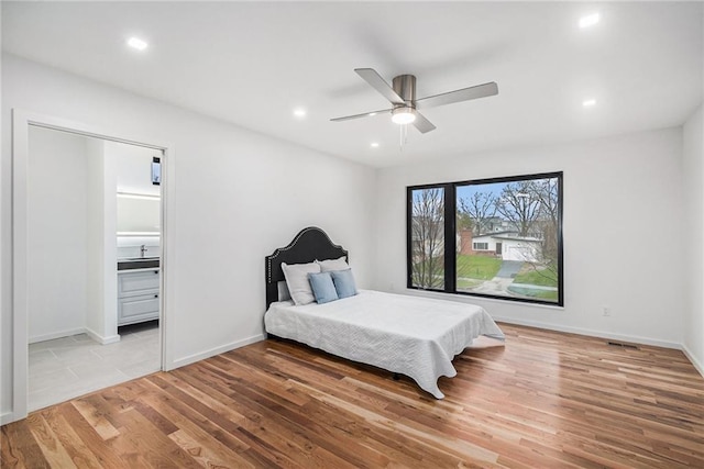 bedroom with connected bathroom, ceiling fan, and light hardwood / wood-style flooring