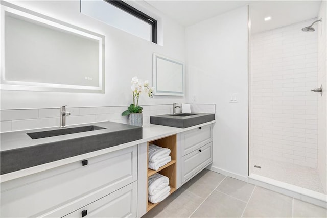 bathroom with tile patterned flooring, vanity, and tiled shower