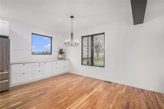 unfurnished dining area featuring a notable chandelier and light hardwood / wood-style floors