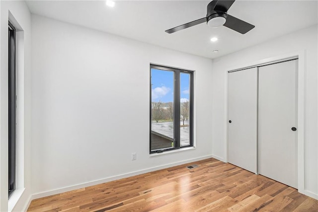 unfurnished bedroom featuring ceiling fan, light wood-type flooring, and a closet