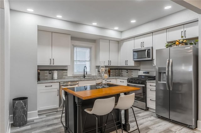 kitchen featuring a breakfast bar area, white cabinetry, sink, and appliances with stainless steel finishes