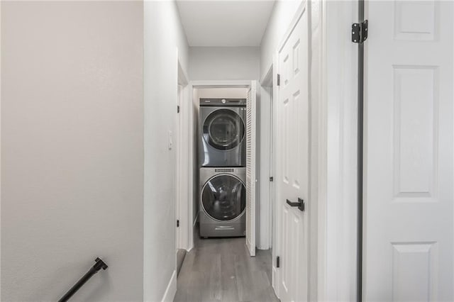 laundry area with stacked washer / drying machine and light wood-type flooring