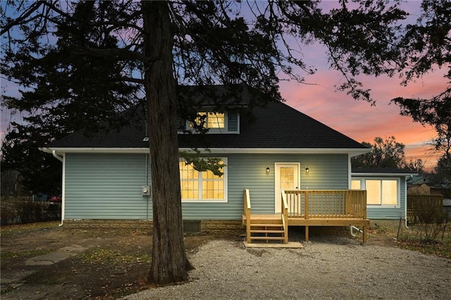 back house at dusk with a wooden deck