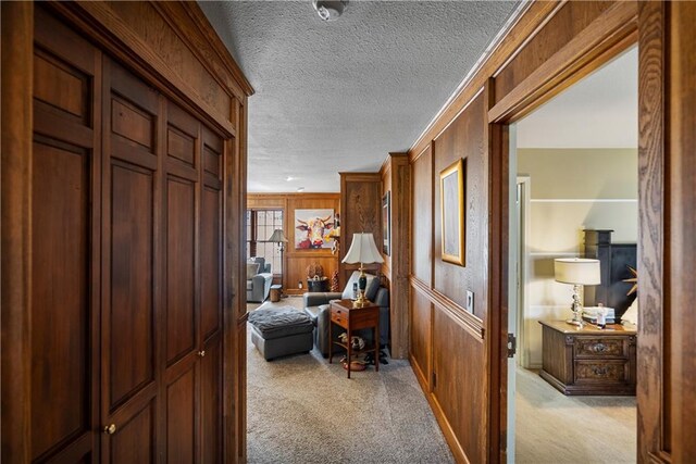 401 Taylor Rd, Independence, KS 67301 - corridor featuring a textured ceiling, light carpet, and wood walls