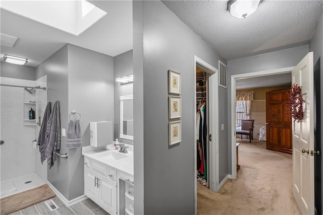 401 Taylor Rd, Independence, KS 67301 - bathroom with vanity, tiled shower, a skylight, a walk in closet, and a textured ceiling