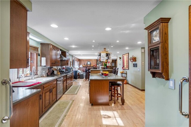 401 Taylor Rd, Independence, KS 67301 - kitchen featuring wall chimney exhaust hood, a kitchen breakfast bar, a sink, stainless steel dishwasher, and a center island