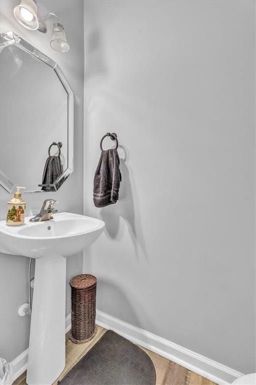 bathroom featuring baseboards, wood finished floors, and a sink