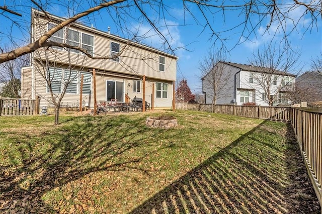 back of house with a fenced backyard, a lawn, a patio, and a fire pit