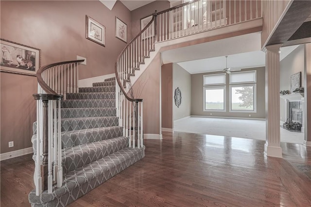 entrance foyer featuring decorative columns, ceiling fan, a towering ceiling, and hardwood / wood-style flooring