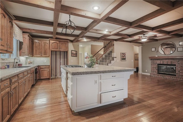 kitchen featuring a brick fireplace, ceiling fan, a center island, and sink