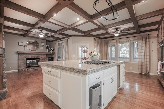 kitchen featuring stainless steel appliances, a kitchen island, a fireplace, white cabinets, and light wood-type flooring