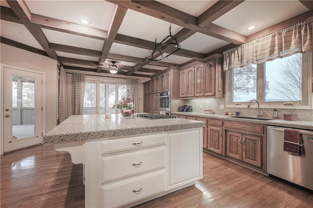 kitchen with ceiling fan, sink, stainless steel appliances, a kitchen island, and light wood-type flooring