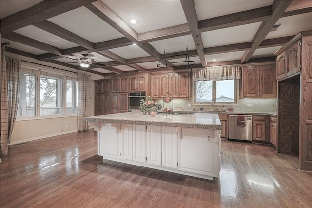 kitchen featuring dishwasher, dark hardwood / wood-style flooring, backsplash, an island with sink, and a breakfast bar