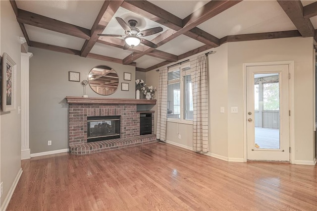 unfurnished living room with beamed ceiling, ceiling fan, light wood-type flooring, and a brick fireplace