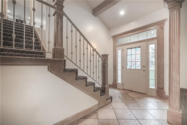 entrance foyer featuring ornate columns, light tile patterned floors, and lofted ceiling with beams