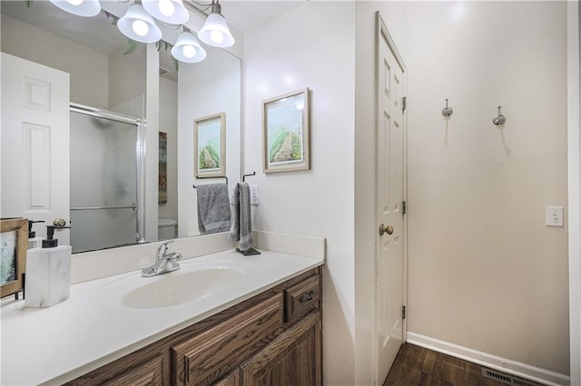 bathroom with hardwood / wood-style floors, vanity, and an enclosed shower