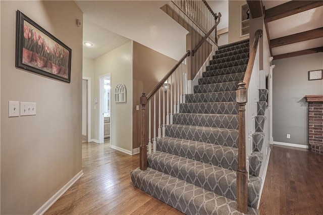 stairway featuring beam ceiling and hardwood / wood-style flooring