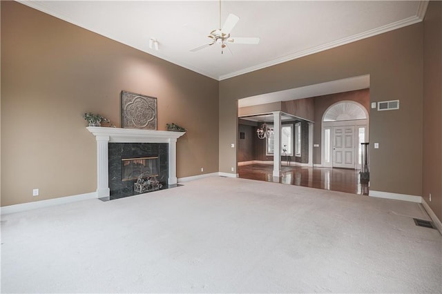 unfurnished living room featuring carpet flooring, ceiling fan with notable chandelier, ornamental molding, and a fireplace