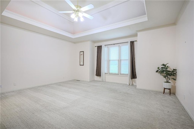 spare room featuring a tray ceiling, ceiling fan, crown molding, and light colored carpet