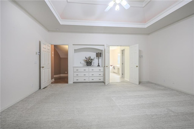 unfurnished bedroom with ceiling fan, crown molding, lofted ceiling, a tray ceiling, and light carpet