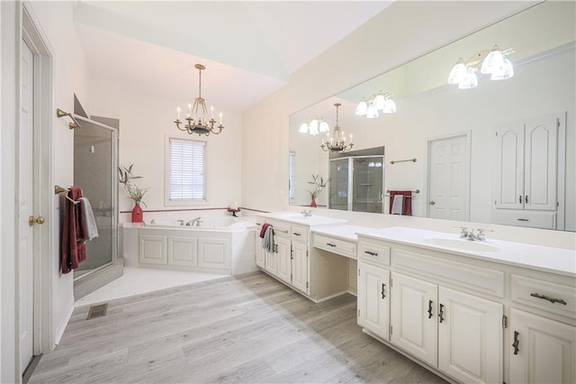 bathroom featuring vanity, vaulted ceiling, independent shower and bath, a notable chandelier, and hardwood / wood-style floors