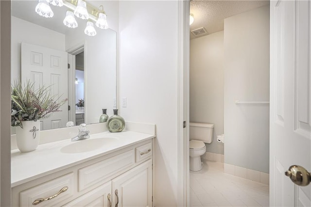 bathroom featuring tile patterned flooring, vanity, a textured ceiling, and toilet