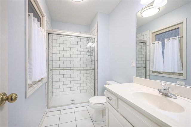 bathroom featuring tile patterned floors, a shower with door, vanity, and toilet